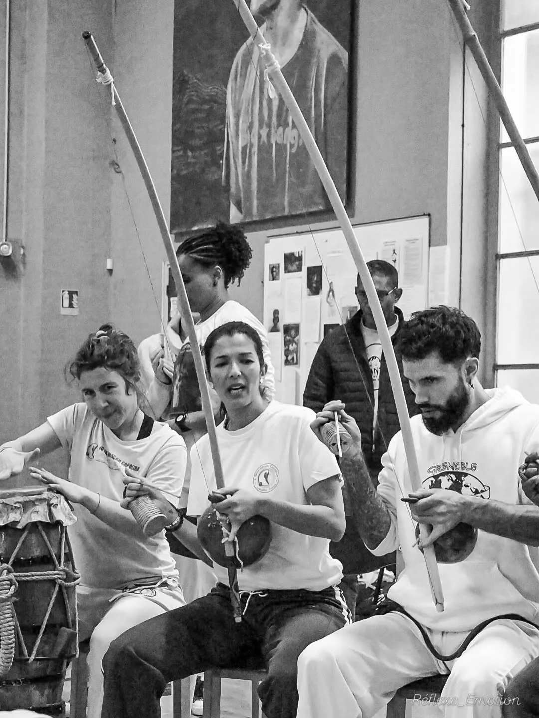 Des musiciens jouent du berimbau dans une photographie en noir et blanc de la roda.