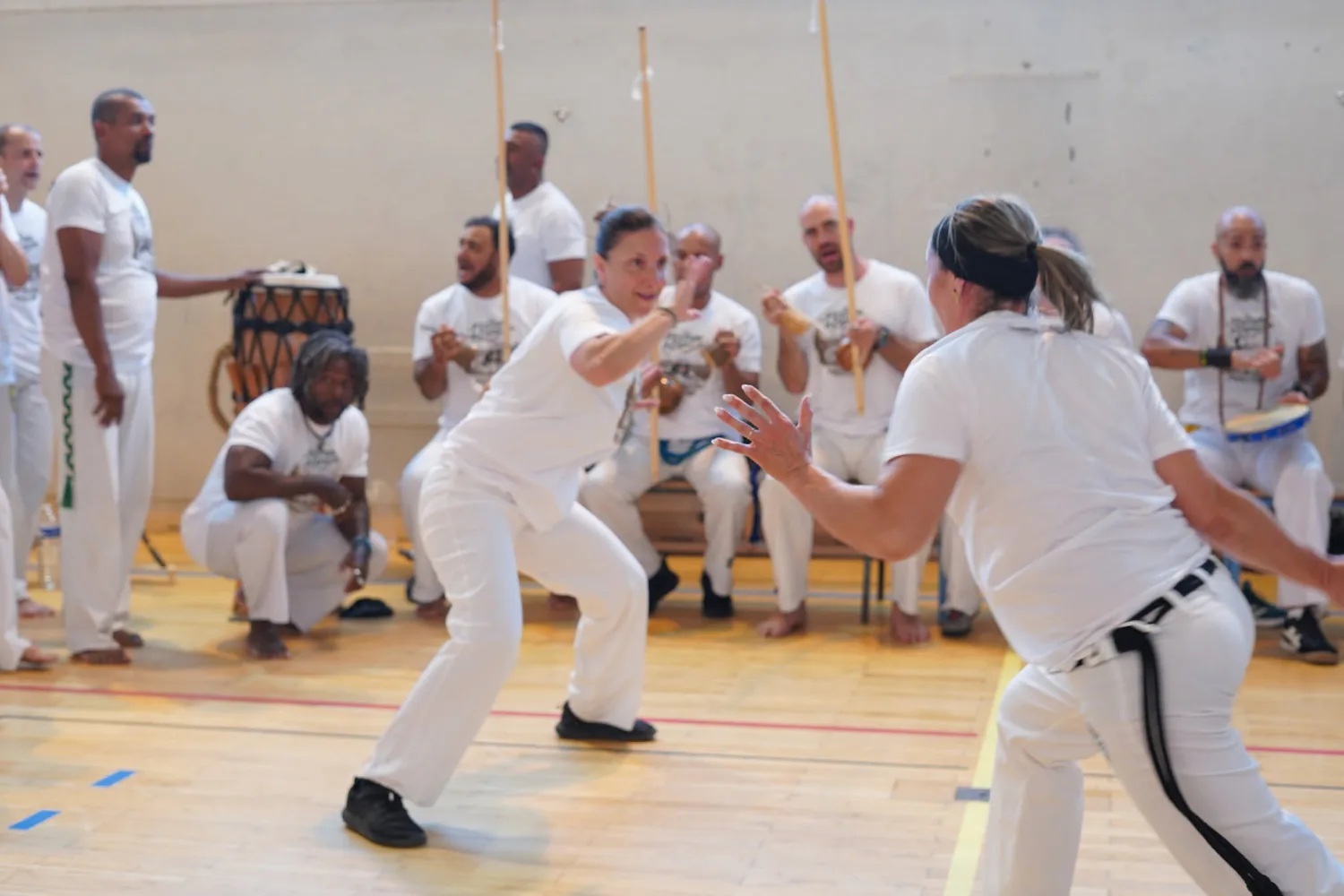 Deux capoeiristes se font face dans la roda, accompagnées par les chanteurs et les berimbaus.