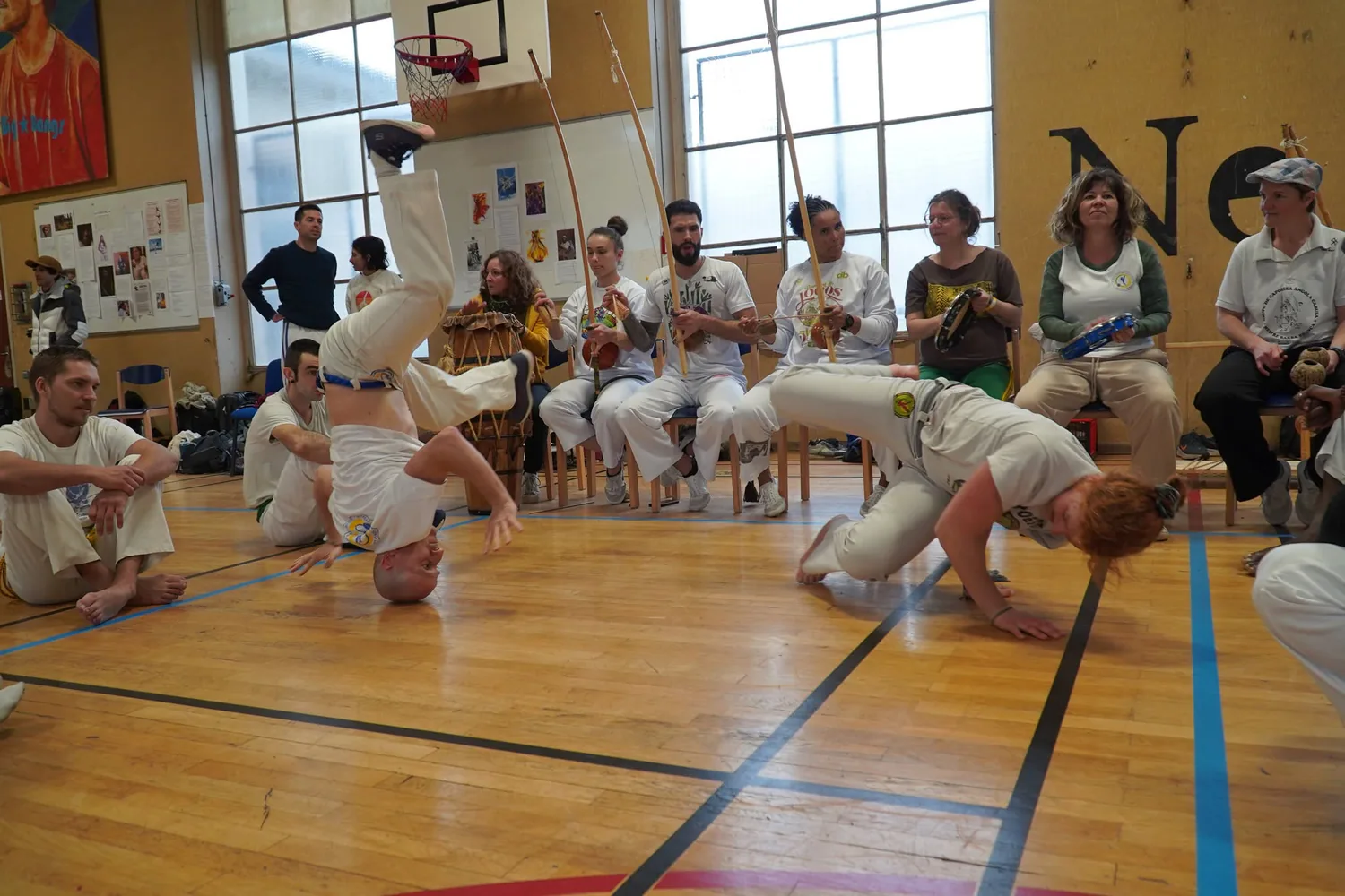 Deux capoeiristes échangent des mouvements au sol devant les musiciens de la roda.