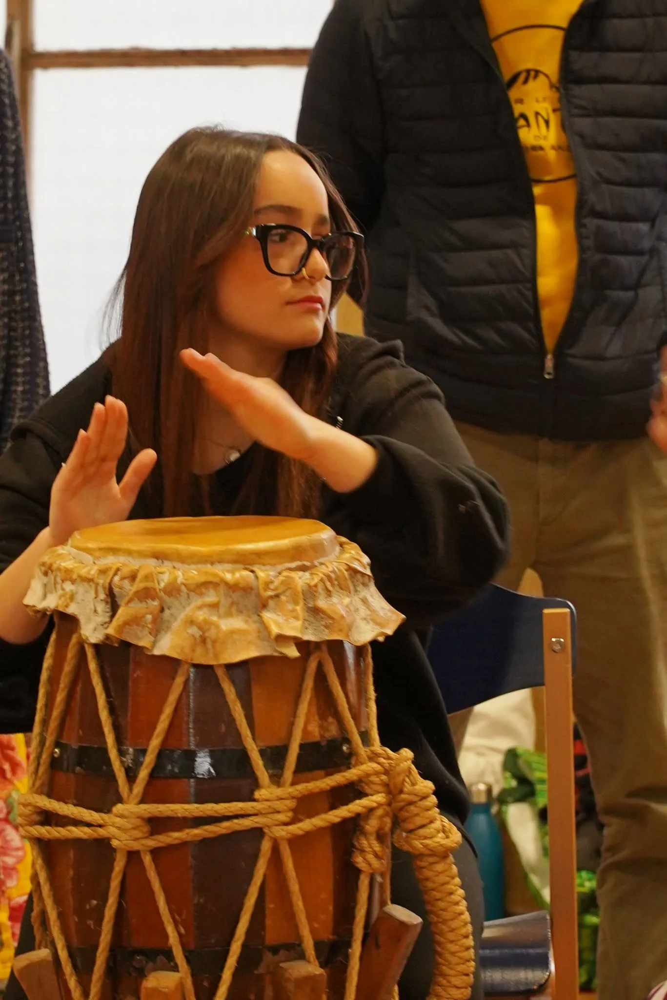 Une jeune musicienne joue de l’atabaque, les mains levées au-dessus de la peau.