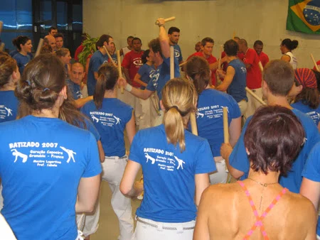 Participants in blue and red T-shirts gathered in the batizado hall.