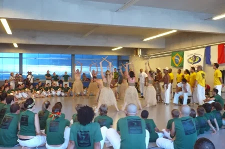 Participants gathered in a circle around a group raising their arms in the hall.