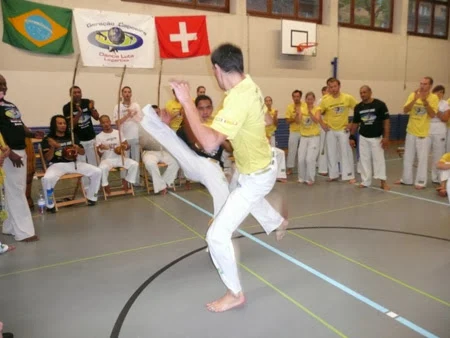 Due capoeiristi con magliette gialle giocano al centro della roda a Zurich.
